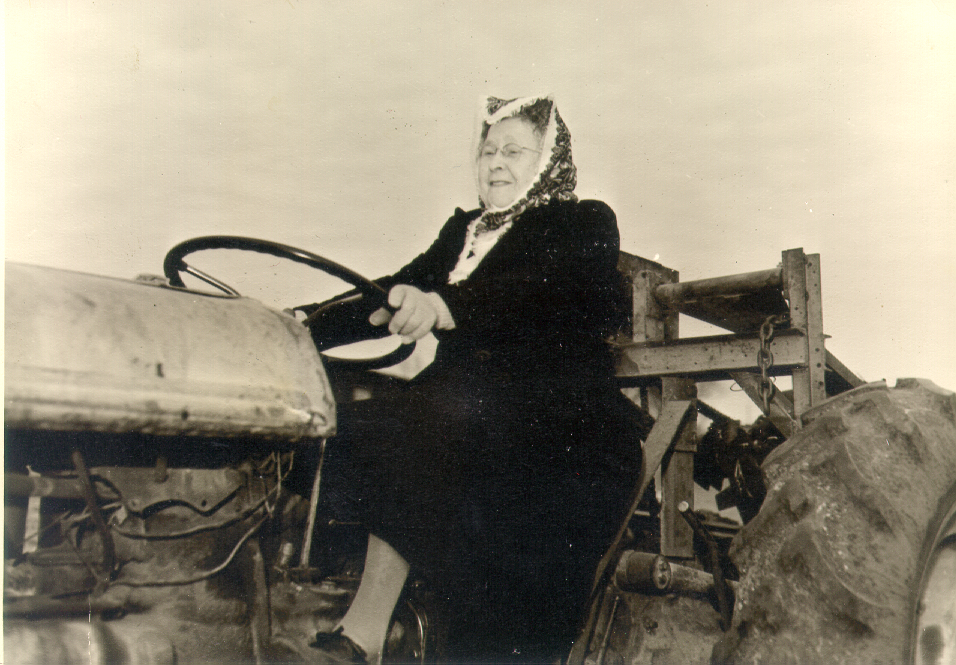 An elderly woman, identified as 75-year-old Alice Kalb, is sitting on an old tractor, holding the steering wheel and smiling. The photo, seemingly black and white, exudes a timeless charm.