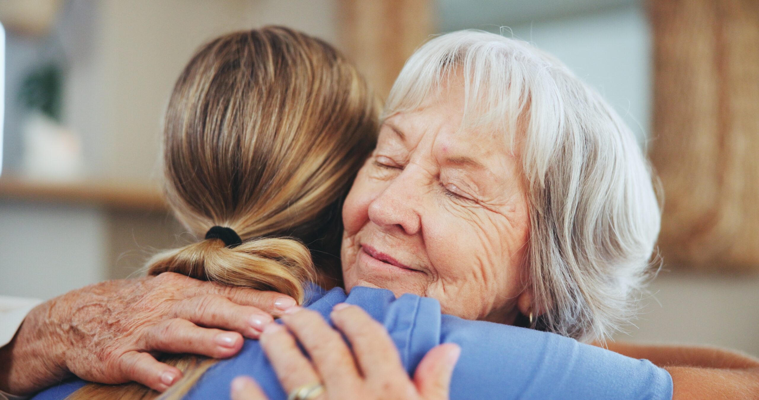 Elderly woman hugging caregiver who appears to be female nurse